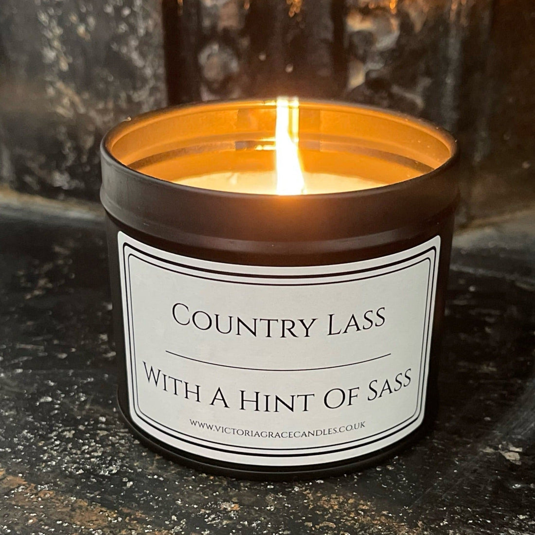 Black tin candle with the words country lass with a hint of sass written on the label