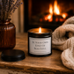 Luxury inspirational candle beside a glowing fireplace with a cosy knitted blanket, creating a warm and comforting setting.