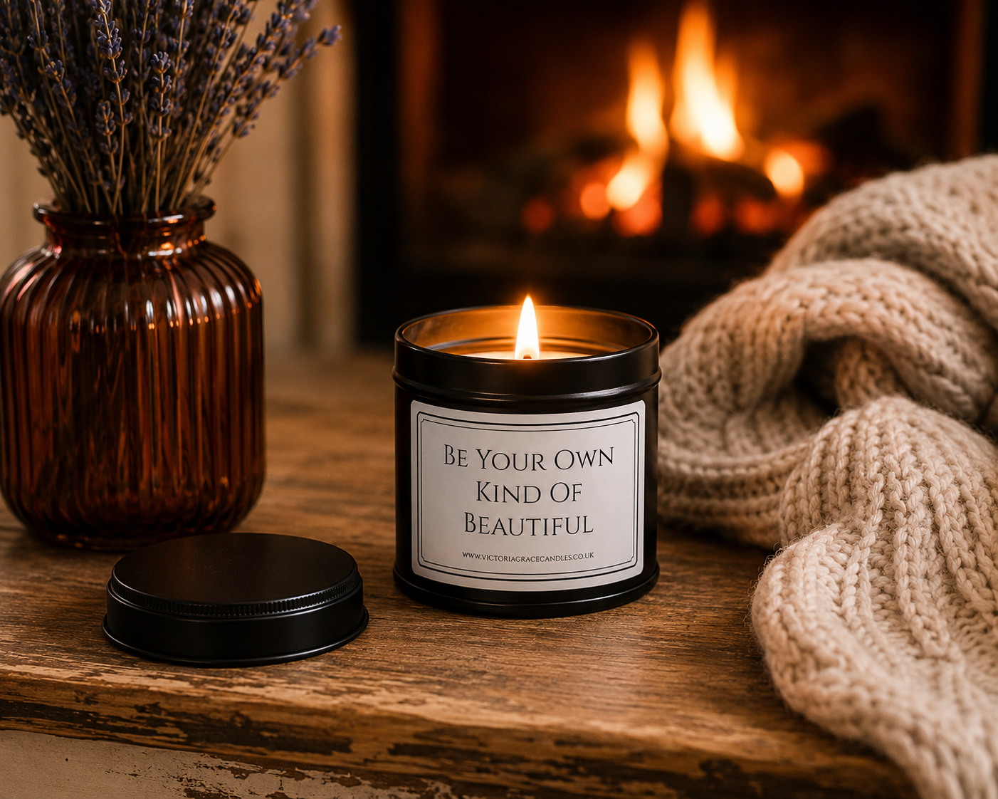 Luxury inspirational candle beside a glowing fireplace with a cosy knitted blanket, creating a warm and comforting setting.