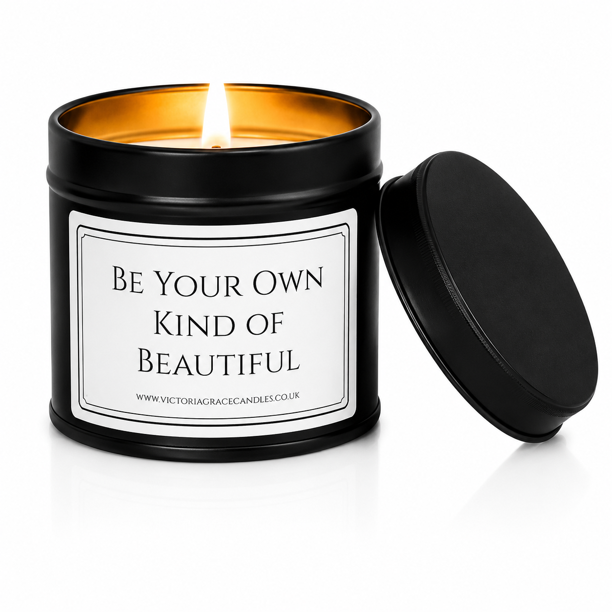Luxury black soy wax candle with the words "Be Your Own Kind of Beautiful" on a white background with the black lid resting beside the candle.