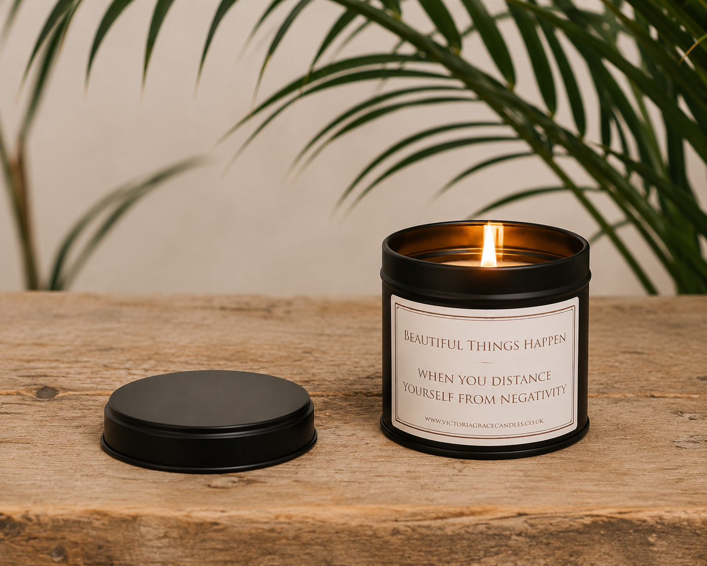 Luxury inspirational soy wax candle displayed on a rustic wooden table beneath tropical green leaves, creating a calm and uplifting atmosphere.