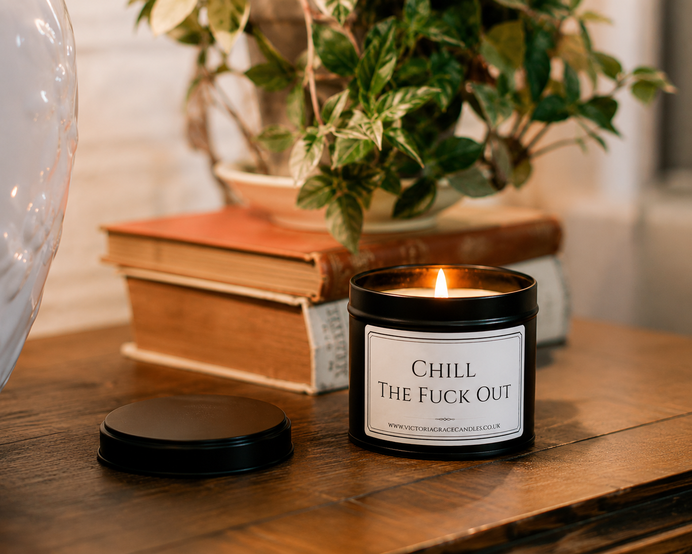 Luxury black soy wax candle displayed on a wooden table with books and greenery in a cosy home setting.