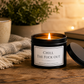 Luxury black soy wax candle beside a cosy blanket, mug and warm ambient lighting, creating the perfect relaxing evening setting.