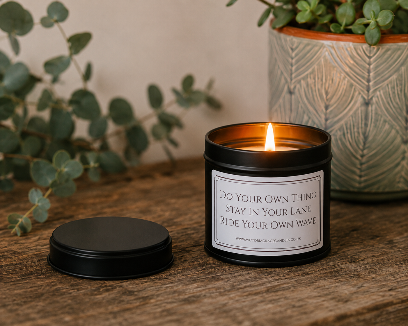 Luxury inspirational soy wax candle displayed on a rustic wooden table with eucalyptus and a textured ceramic plant pot, creating a calm and uplifting atmosphere.