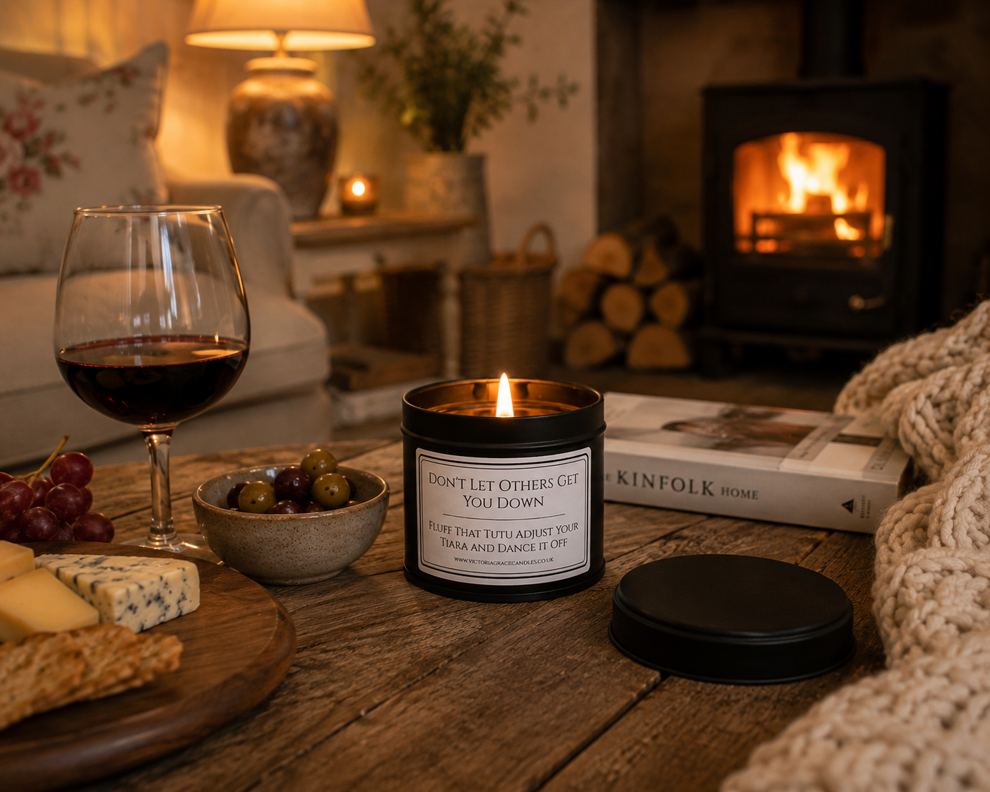 black tin candle with the words don't let others get you down on it set in a cosy sitting room with a log burner in the background