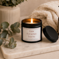 Luxury soy wax candle displayed on a marble tray with eucalyptus, soft blankets and spa-inspired home décor, creating a calm and luxurious atmosphere.