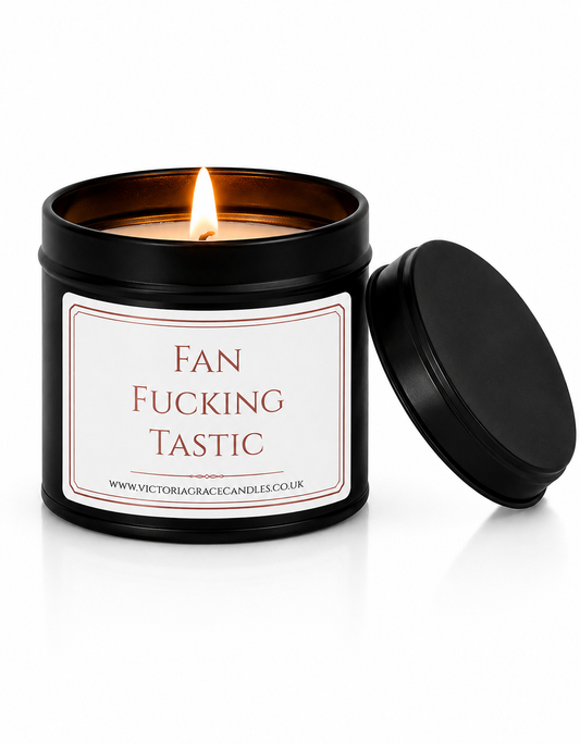 Luxury black soy wax candle with the words "Fan Fucking Tastic" displayed on a white background with the black lid resting beside the candle.