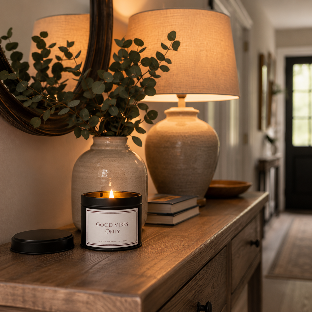 Good Vibes Only candle displayed on a rustic hallway sideboard beside a beautiful table lamp creating a warm welcoming entrance