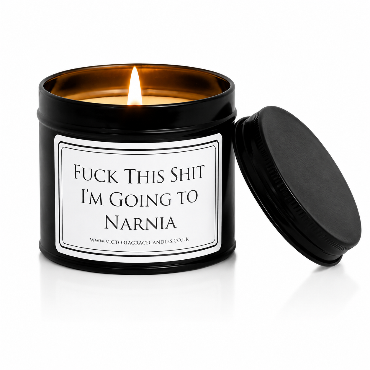 Luxury black soy wax candle with the words "Fuck This Shit, I'm Going to Narnia" on a white background with the black lid resting beside the candle.
