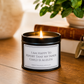 A black metal candle tin with a lit flame sits on a wooden table. The front label reads, 'I AM HAPPY TO REPORT THAT MY INNER CHILD IS AGELESS.