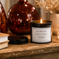 Luxury black soy wax candle on a rustic wooden table with warm home décor, creating a cosy and inviting atmosphere.