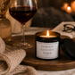 Luxury soy wax candle beside a glass of red wine, chocolates and a soft blanket, creating the perfect relaxing evening setting.