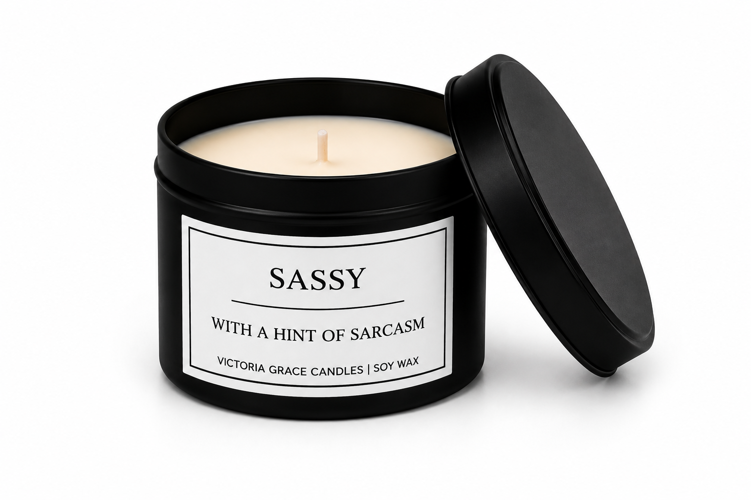 A black metal candle tin with its lid propped open, showing a creamy off-white soy wax candle inside. The front label reads 'SASSY WITH A HINT OF SARCASM' and 'VICTORIA GRACE CANDLES | SOY WAX'.