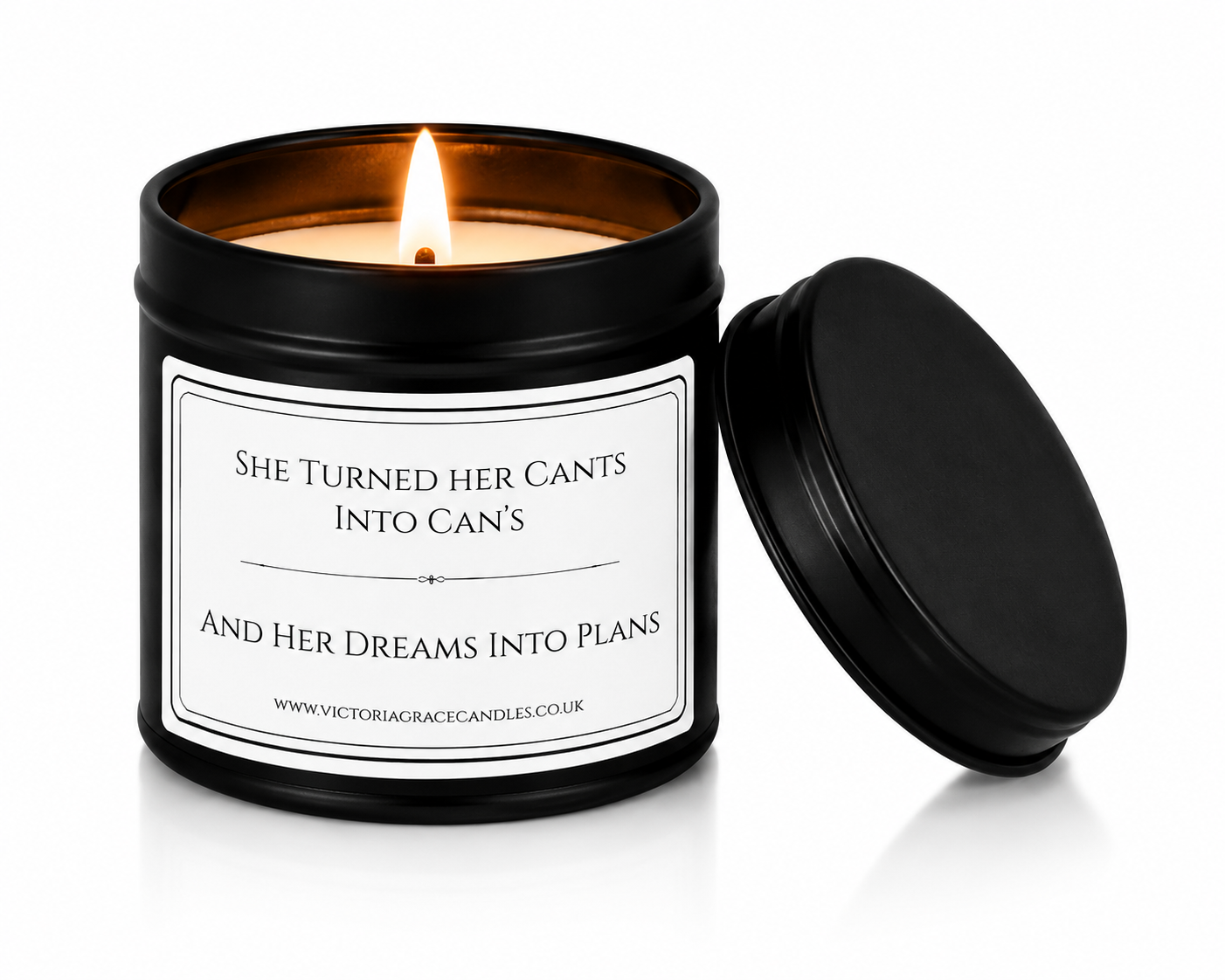 A black metal candle tin with a lit candle inside and the lid resting beside it on a white background. The front label reads, 'SHE TURNED HER CANTS INTO CAN'S AND HER DREAMS INTO PLANS'