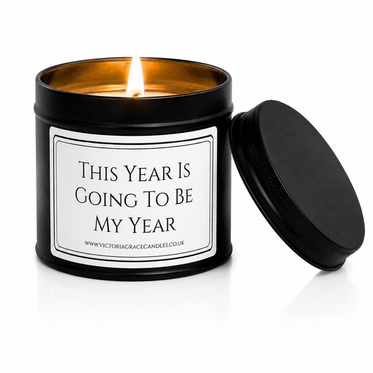 Luxury black soy wax candle with the words "This Year Is Going To Be My Year" on a white background with the black lid resting beside the candle.