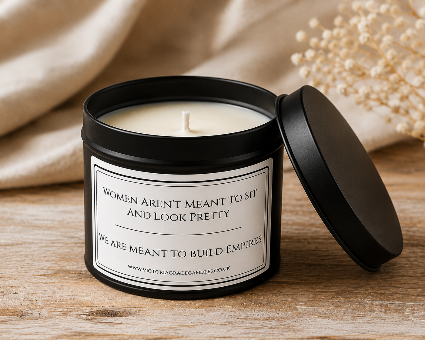 Women Build Empires soy candle in an open matte black tin styled on a rustic wooden table with soft neutral home décor.