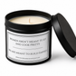 An open black metal candle tin with cream-colored wax and a lid leaning against it on a white background. The front label reads, 'WOMEN AREN'T MEANT TO SIT AND LOOK PRETTY WE ARE MEANT TO BUILD EMPIRES' with the brand Victoria Grace Candles visible at the bottom.