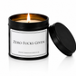 Luxury black soy wax candle with the words "Zero Fucks Given" displayed on a white background with the black lid resting beside the candle.