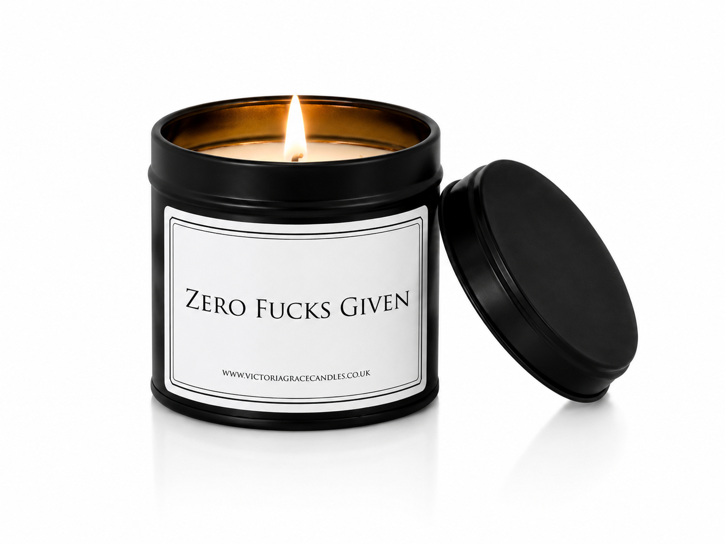 Luxury black soy wax candle with the words "Zero Fucks Given" displayed on a white background with the black lid resting beside the candle.